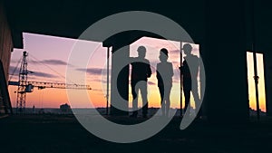 Builders stand in a house on a sunset background. Construction contractor working on a construction site.