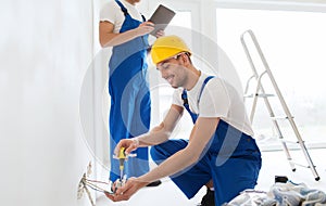 Builders with tablet pc and fixing wiring indoors