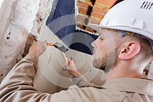 Builders using hammer to remove walls plaster