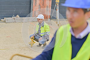 Builders using measuring tools outdoors in construction site
