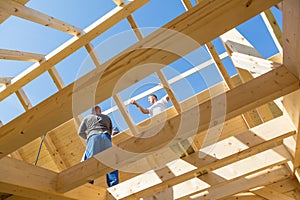 Builders at work with wooden roof construction.