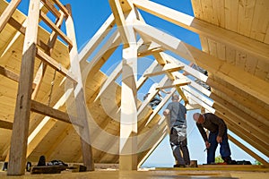 Builders at work with wooden roof construction.