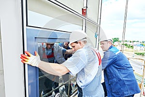 Builders worker installing glass windows on facade