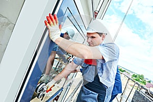 Builders worker installing glass windows on facade