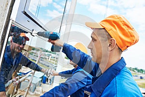 Builders worker installing glass windows on facade