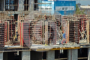 Builders are working on a construction site, assembling the frame of a high-rise building from rebar, cement blocks and others