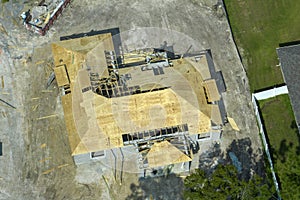 Builders working on roof construction of unfinished residential house with wooden frame structure in Florida suburban