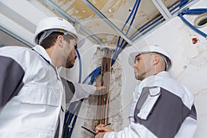 Builders working with water pipes in boiler room