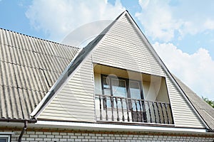 Building attic house construction with asbestos roof, cozy balcony and siding facade