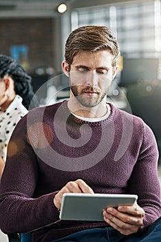 Building a brand using online tools. a young man using a digital tablet in an office.