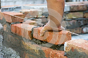 Building brick block wall on construction plant. Worker builds a brick wall in the house. Construction worker laying bricks on ext