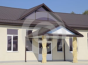 building with a brown roof. The main entrance to the house. Modern materials of finish and roofing.