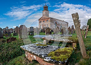 Building and cemetery stones of Kirkandrews under the blue sky with clouds in Carlisle