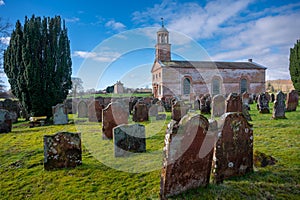 Building and cemetery stones of Kirkandrews under the blue sky with clouds in Carlisle