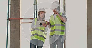 Building in construction with a female and a male engineers using a tablet and mobile phone to visualize the building