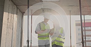 Building in construction with a female and a male engineers using a tablet and mobile phone to visualize the building