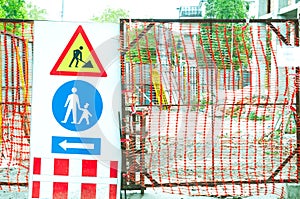 Building construction site gate with warning signs for caution.