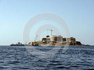 Building construction site on an island with ship and crane view from open water