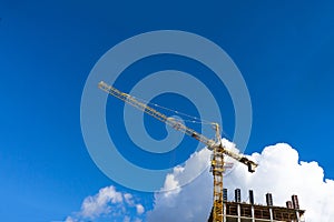 Building construction site with tower crane against blue sky