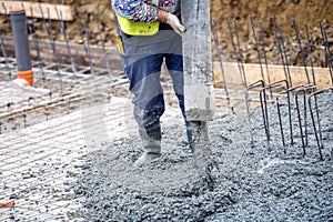 Building construction worker pouring cement or concrete with pump tube photo