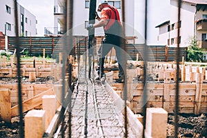 Building construction worker pouring cement or concrete with pump tube. Details of worker and machinery photo