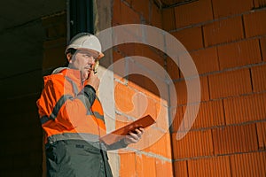 Building contractor and construction engineer making sketches and writing notes on building site