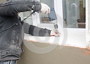 Building contractor drilling hole for insulation plastic holder