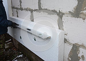 A building contractor installing external wall polystyrene boards insulation using plastic capped fixings is checking if the wall