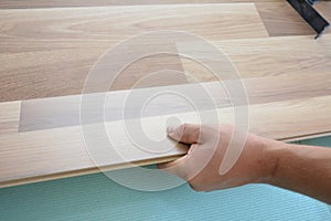 A building contractor is installing wood laminate flooring on underlayment photo