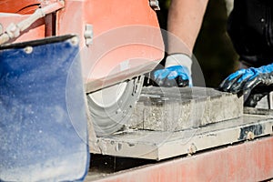 Building contractor using an angle grinder to cut a paving stone