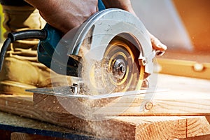 Building contractor worker using hand held worm drive circular saw to cut boards on a new home constructiion project