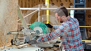 Building contractor worker using hand held worm drive circular saw to cut boards on a new home constructiion project