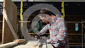 Building contractor worker using hand held worm drive circular saw to cut boards on a new home constructiion project