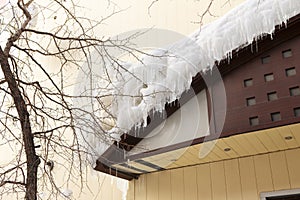 Building covered with big icicles Icicles hang from the roof, vertical ice stalactite hanging from roof Poor thermal