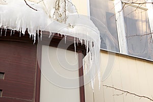 Building covered with big icicles Icicles hang from the roof, vertical ice stalactite hanging from roof Poor thermal