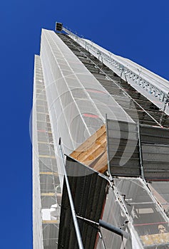 building covered in scaffolding during  installation of insulation panels to safeguard the environment and energy saving