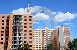 Building crane and building under construction with insulation, paiting walls and building contractors