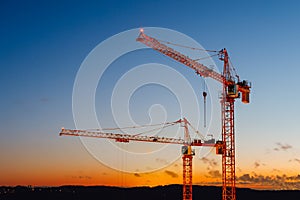 Building cranes on the construction site at sunset background