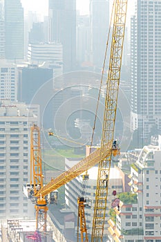 Building crew dissemble tower crane on a hazy day.