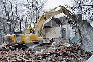 Building demolition. Excavator breaks old two-storey house. Industrial cityscape with destroy process.