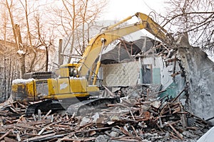 Building demolition. Excavator breaks old two-storey house. Industrial cityscape with destroy process.