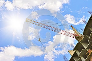 Building with elevating crane and sky with sun