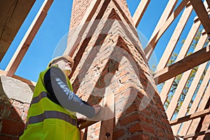 Building engineer standing on ladder looking at roof beams