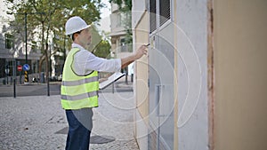 Building expert conducting inventories writing paper outdoors. Electrician man