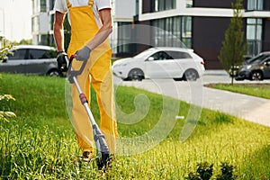 Building exterior at background. Man cut the grass with lawn mover outdoors in the yard