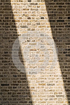 Building exterior, roughly textured brown brick wall with contrast sunligtht background
