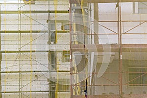 Building facade renovation, old house reconstruction, repair. Scaffold in front of building facade covered with yellow transparent