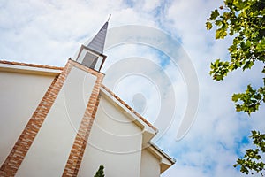 Building facade of a traditional American Protestant church with clock tower and blue sky