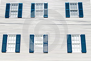 Building facade with white wooden wall, windows and blue shutters in key west, usa. Architecture and design. House front on sunny