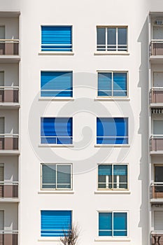 Building facade with windows with blue rolling shutters